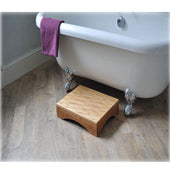 Bamberry bamboo bath step next to a white clawfoot tub with a purple towel over the side, side view.