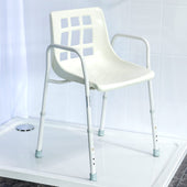 Height adjustable shower chair with armrests and sturdy legs on a tiled shower floor, front angle view.