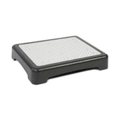 Black and grey plastic outdoor step with textured non-slip surface and four short legs, angled front view.