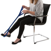 Woman seated using Drive Double Handed Leg Lifter to raise one leg, other foot resting on floor, in use side view.