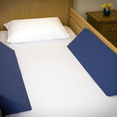 Two large blue wedges with a connecting sheet to help keep someone in bed, side view.