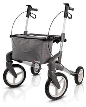 Blue all-terrain rollator with large wheels, ergonomic handles, hand brakes, and grey centre storage bag, front view.