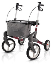 Blue all terrain rollator with large wheels, hand brakes, and grey front storage bag, front view.