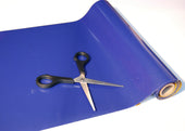 Black-handled scissors on a roll of red Tenura non-slip reel, close-up view.