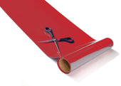 Black scissors with non-slip handles on a red Tenura non-slip reel, unrolled on a white surface, top view.