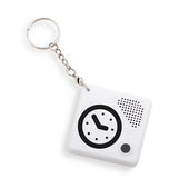 White square keychain with clock face print, black button, speaker holes and metal ring, designed for easy time telling; front view.