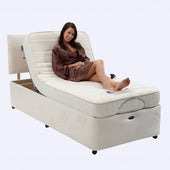 Restwell Richmond electric bed and mattress set with elevated headrest, woman in brown polka dot robe sitting up, in use view.