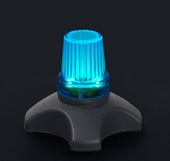 White quad cane tips with glowing blue LED and ribbed tops, placed on a dark base against a black background, close-up.