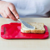 White ORNAMIN non-slip cutting board in use with a person buttering bread, top view.