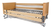 Woburn Profiling Bed with wooden headboard, footboard, metal frame, side rails and wheels, side view.