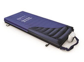 Blue-covered dynamic mattress with attached pump for pressure relief, side view.