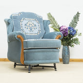 Blue floral armchair with a fixed height chair raiser next to a vase of purple, blue, and white flowers, front view.