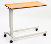 Low height overbed table with wooden top, metal frame and black caster wheels, shown from a side angle.