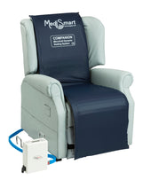Light grey riser recliner chair with alternating pressure surface, connected to white device by a blue tube, side view.