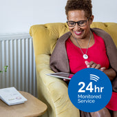 Medequip Connect 24hr Monitored Telecare Service unit in use next to woman with tablet, side view.