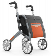 Black Trust Care Let’s Shop rollator with four wheels, black handles and an orange shopping bag, front view.