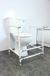 NRS Nuvo adjustable width toilet frame with non-slip feet, shown freestanding on tiled floor, front angled view.