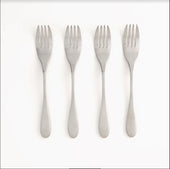 Set of four stainless steel Buckingham Knork forks, evenly spaced and facing up on a white background, top view.
