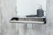 Shelf grab rail with soap dispenser and dish, mounted below a mirror on a concrete wall, front view.