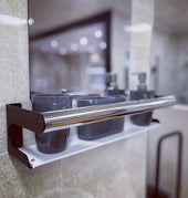 Elegance Caddy Grab Rail with two dark cups and pump bottles on a tiled wall, mirror in background, front view.
