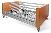 Bariatric bed with metal slats, wood ends, and wheels for easy movement, side view.