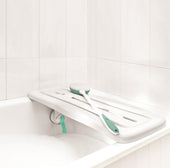 Surefoot Shower Board with green handles placed across a bathtub, matching bath brush resting on board, top view.