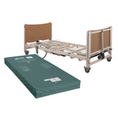 Sidhil Solite Pro electric bed with mattress next to a green castellated foam mattress on the floor, side view.