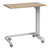 Overbed table with oak wood top, metal frame, gas lift and four castors for easy movement, shown from side angle.