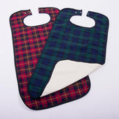 Two adult clothing protectors in red and green plaid with snap fastenings and waterproof backing, laid flat side by side, top view.