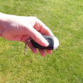 Lifemax Rechargeable Personal Alarm with SOS button and keyring torch held in a hand over grass, in use view.