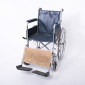 Wheelchair calf strap with a tan wool footrest cover on a plain white background, front view.