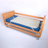 Wooden hospital bed with side rails, blue mattress, and a wool pile under blanket on top, side view.