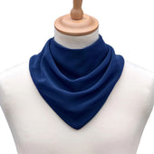 Royal blue neckerchief style dribble bib on a white mannequin with wooden stand, front view.