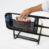 Magazine and blue item in mesh pockets on black Easyfit Bedguard, hand placing magazine, in use close-up.