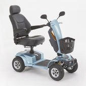 Motion Healthcare Xcite mobility scooter in aqua with black seat, armrests, handlebars and front basket, shown from the side.