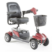 Red mobility scooter with padded seat, armrests, four wheels, handlebars and front basket, side view.
