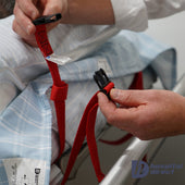 Red straps being fastened to a Hospital Direct Satin SIBA 4-Way Top Draw Sheet with security loops on hospital bed, close-up.