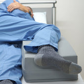 Rectangular Hospital Direct HD Deluxe Limb Pad supporting one leg, person in blue trousers and grey socks, in use side view.