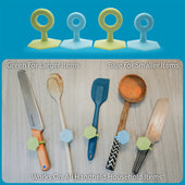 Blue and green single handed grip toggle aids attached to a knife, spoon, and spatula, in use view.