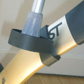 Trust Care crutch holder clipped to Lets Move rollator frame, black clips visible, wooden floor background, close-up.