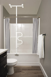 Bathroom with Stander Bath Security Pole and Curved Grab Bar next to white tub, grey shower curtains, wide front view.