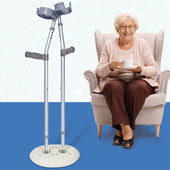 Crutch Caddy holding crutches upright beside an elderly woman seated in a chair, cracked floor, in use view.