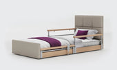 Profiling floor bed in anthracite fabric with wooden side rails and padded headboard, front angle view.