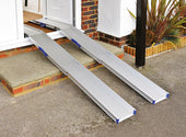 Pair of Ultralight Combi Channel Ramps bridging an outdoor step up to a house entrance, in use.