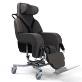 Dark grey tilt-in-space chair with armrests, headrest, support straps, leg support and wheels, pressure relief feature, side view.