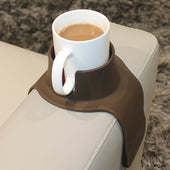 Black CouchCoaster anti-spill drink holder with a white mug on a light sofa armrest, in use view.