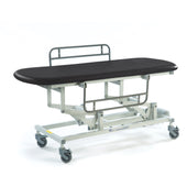Black electric changing table with height-adjustable top, sturdy frame and four wheels, side view.