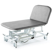 Light grey hydraulic therapy Bobath couch with padded top, metal frame and wheels for moving, side view.