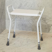NRS shower stool with handles, metal legs and rubber tips on bathroom floor by tiled wall, front angle.
