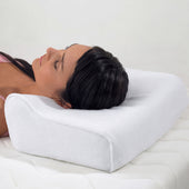 Woman lying on a mattress using the Harley Designer Pillow for head and neck support, in use view.